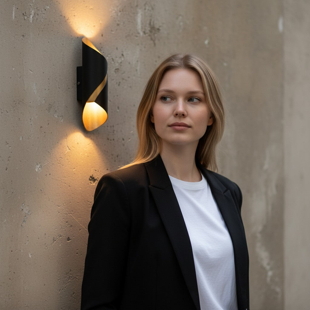 Applique murale extérieure LED Lumeoo noire et dorée au design moderne sur un mur en béton avec une femme élégante