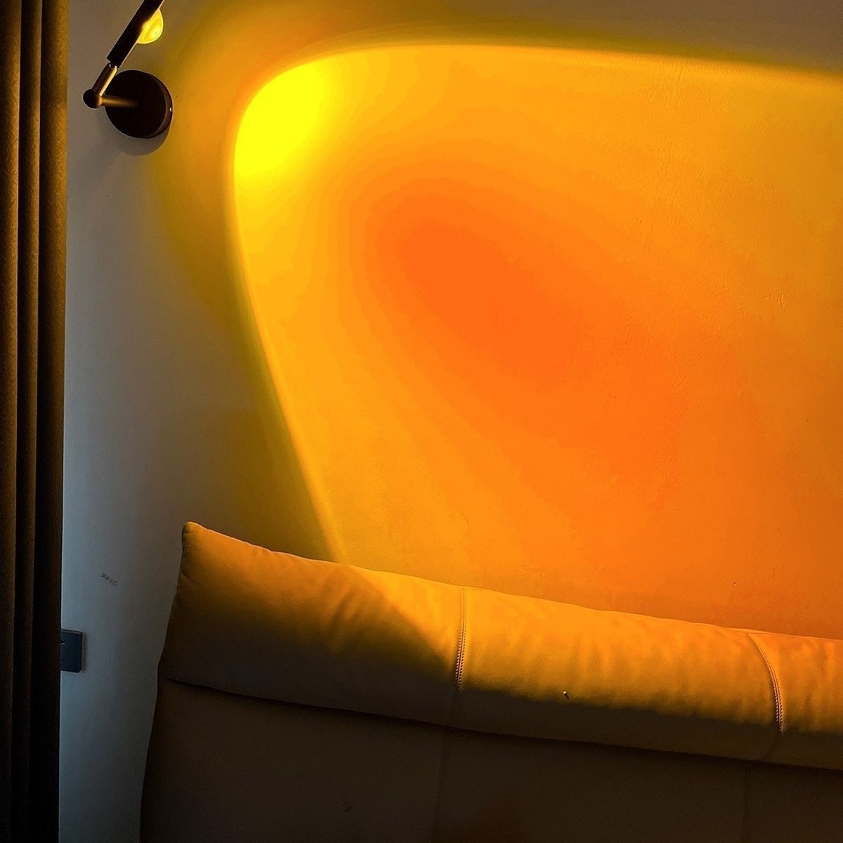 Applique murale Lumeoo SUNWALL LED projetant une lumière chaude de coucher de soleil sur un mur de chambre