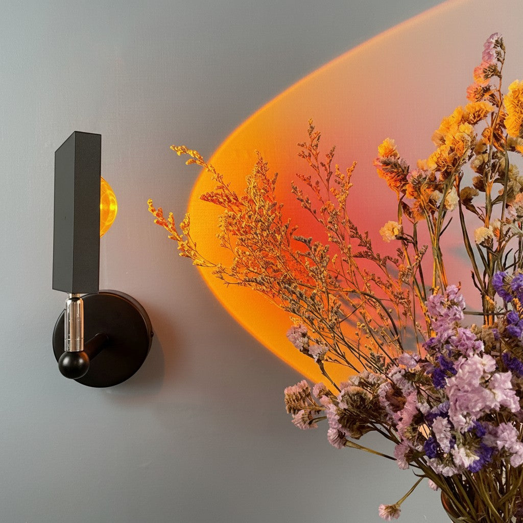 Applique murale Lumeoo SUNWALL noire projetant une lumière coucher de soleil chaude près d'un bouquet de fleurs séchées