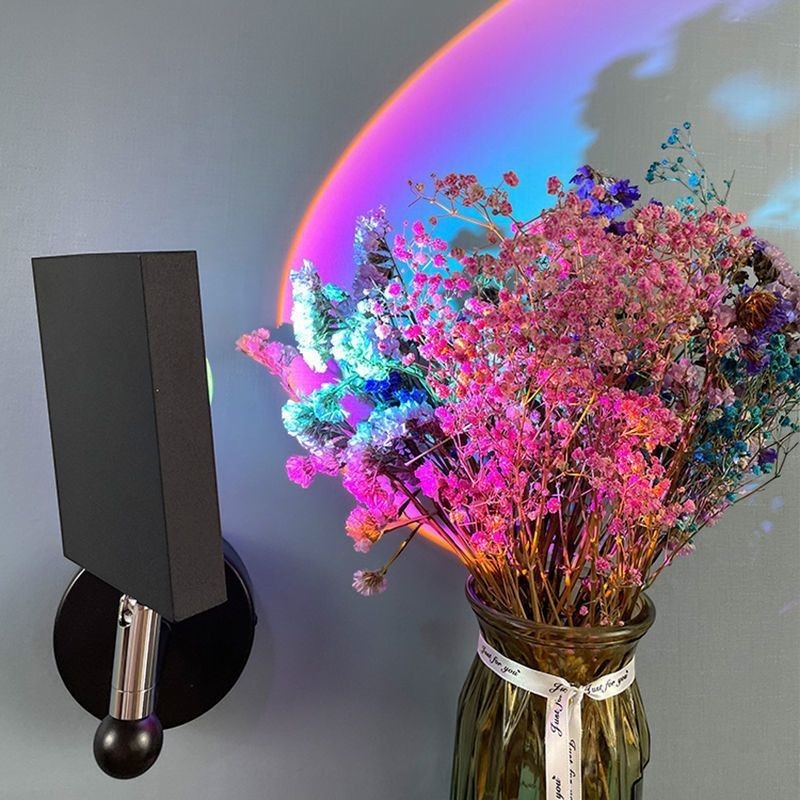 Applique murale LED Lumeoo SUNWALL projetant un halo coucher de soleil coloré derrière un bouquet de fleurs séchées