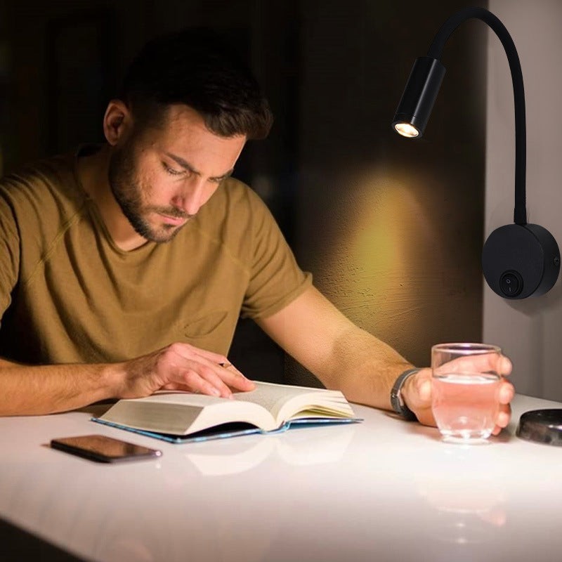 Homme lisant un livre sous une applique murale LED noire Lumeoo à col de cygne flexible et orientable