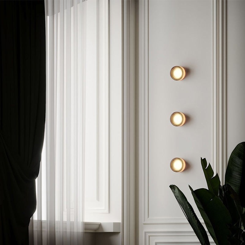 Trois appliques murales LED rondes Lumeoo diffusant une lumière chaude sur un mur mouluré près d'une fenêtre