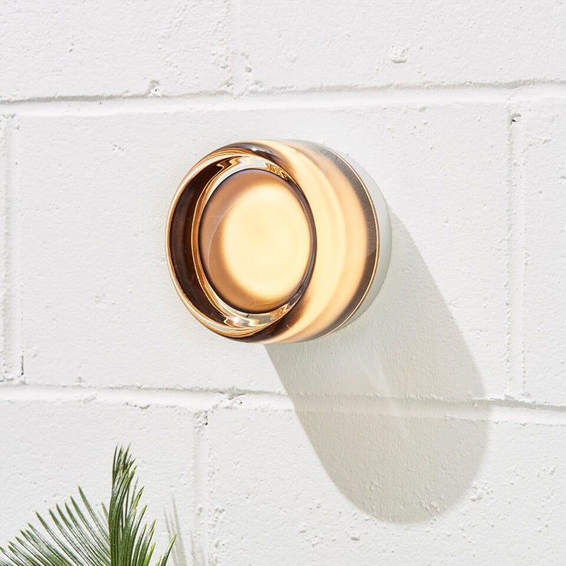 Applique murale LED ronde Lumeoo au design moderne en verre ambré diffusant une lumière chaleureuse sur un mur blanc Image
