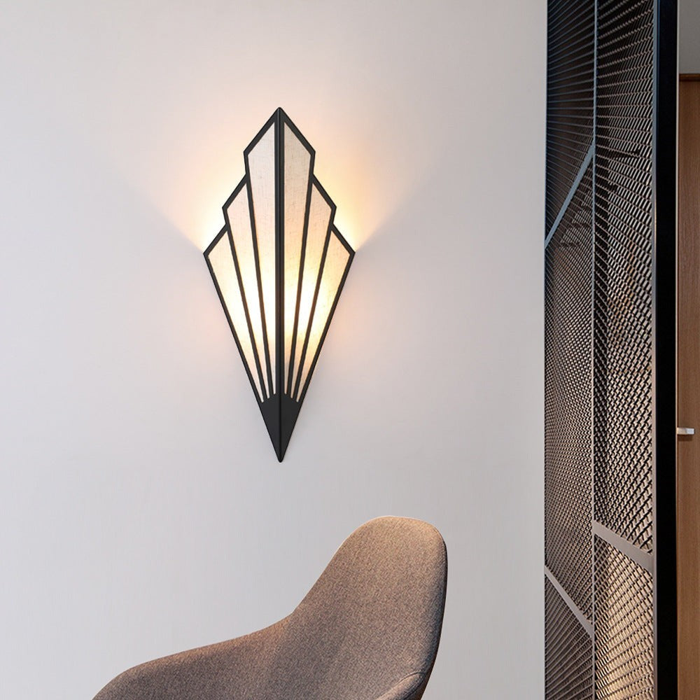Applique murale LED Lumeoo triangulaire au design art déco noir diffusant une lumière douce sur un mur blanc