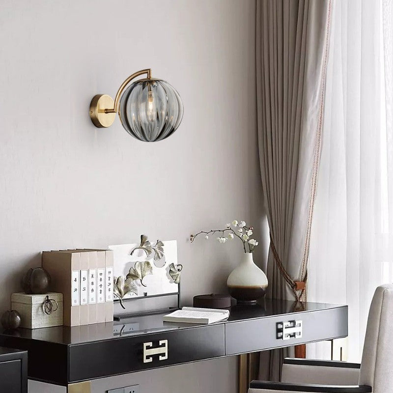 Applique murale Lumeoo avec globe en verre strié gris et support doré, installée dans une chambre élégante.
