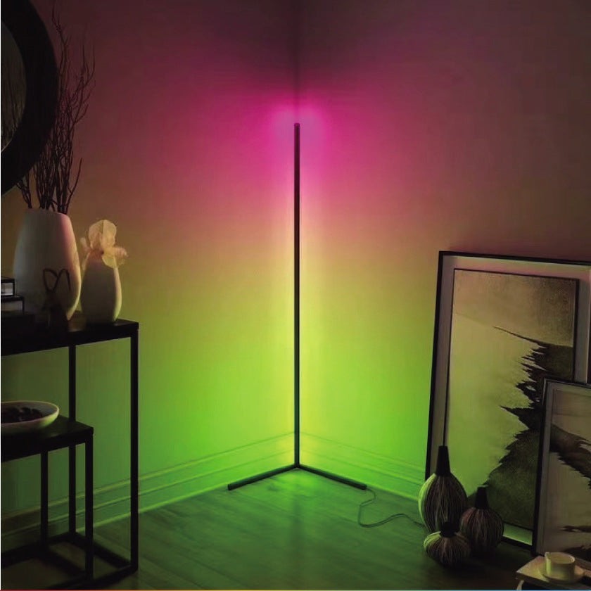 Lampadaire sur pied Lumeoo RGB connecté diffusant une lumière rose et verte dans l'angle d'un salon moderne.