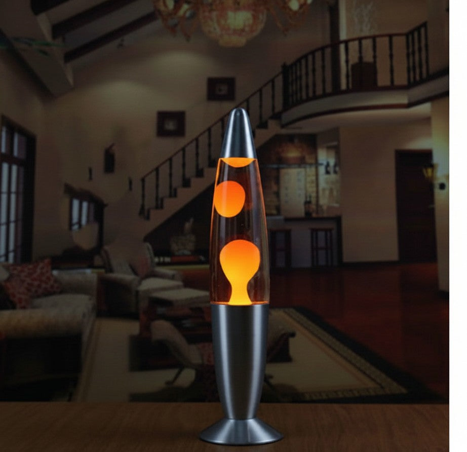 Lampe à lave Lumeoo Vulcano 33cm avec cire orange, base et capuchon en métal argenté dans un salon cosy.