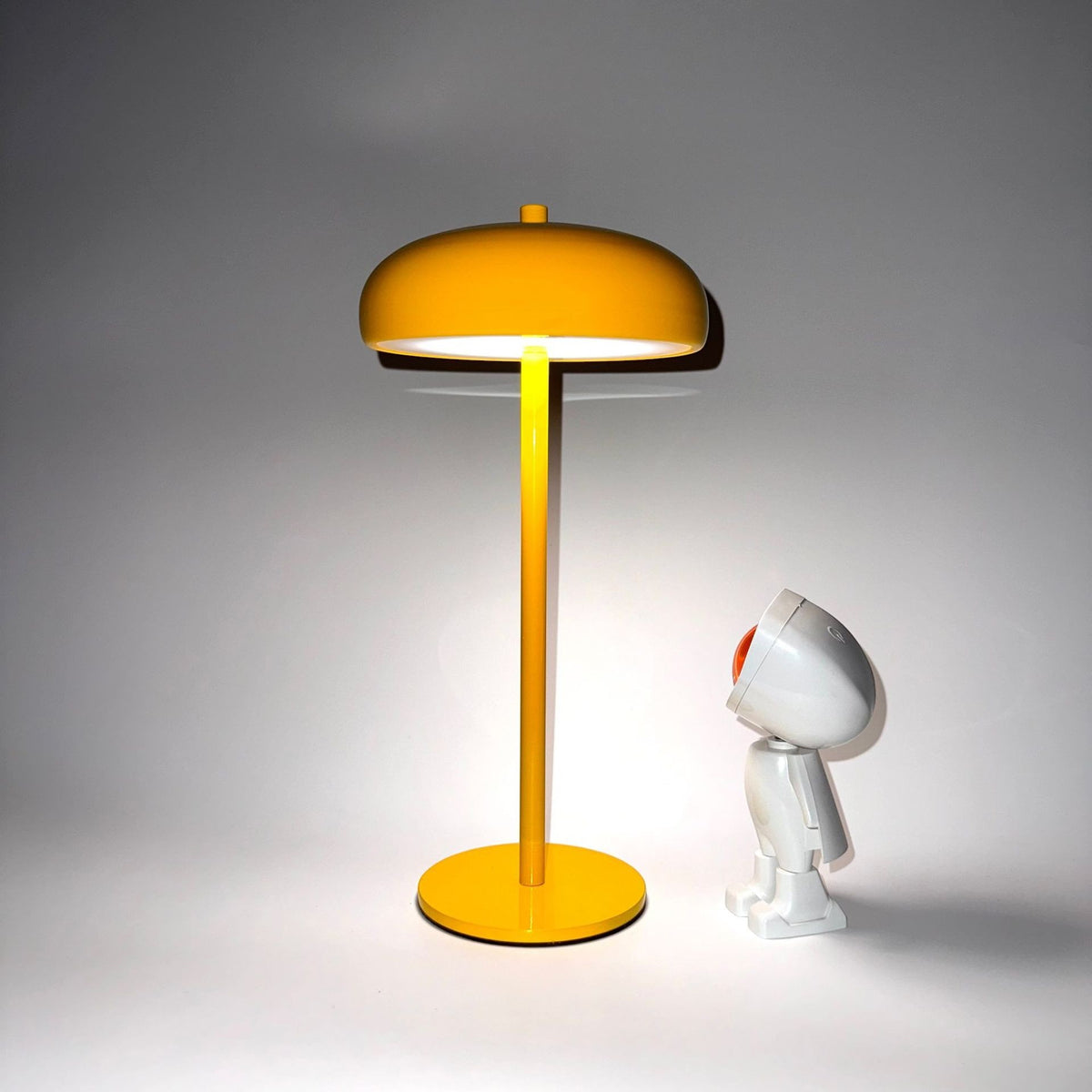 Lampe champignon Lumeoo jaune minimaliste et rechargeable avec une figurine décorative sur fond blanc