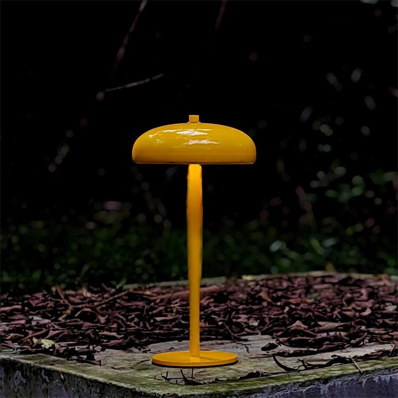 Lampe champignon Lumeoo jaune minimaliste et rechargeable posée sur une surface en extérieur