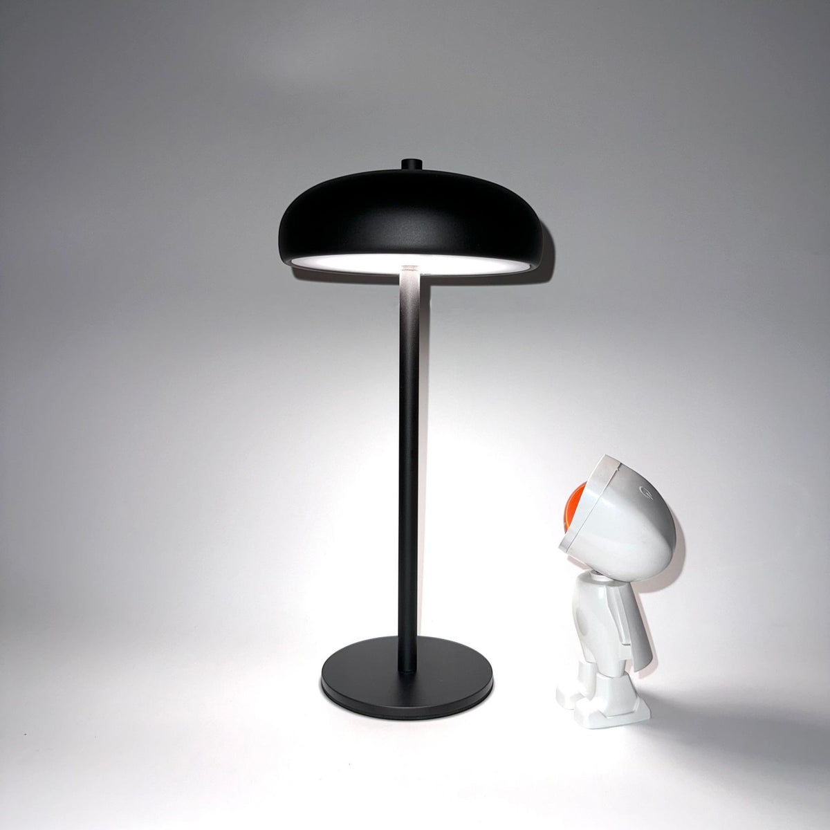 Lampe champignon Lumeoo noire minimaliste et rechargeable avec éclairage LED doux sur fond blanc
