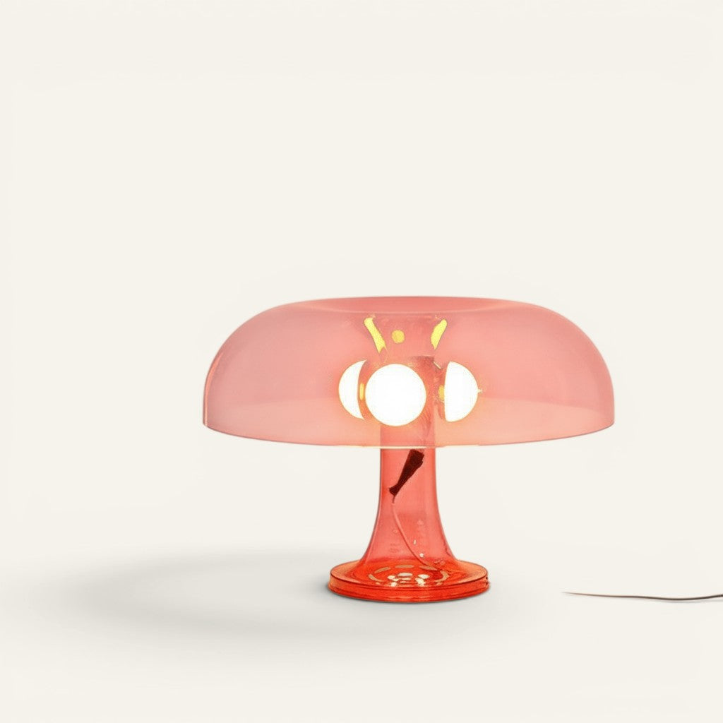 Lampe champignon Lumeoo en verre acrylique orange transparent diffusant une lumière douce sur une table blanche