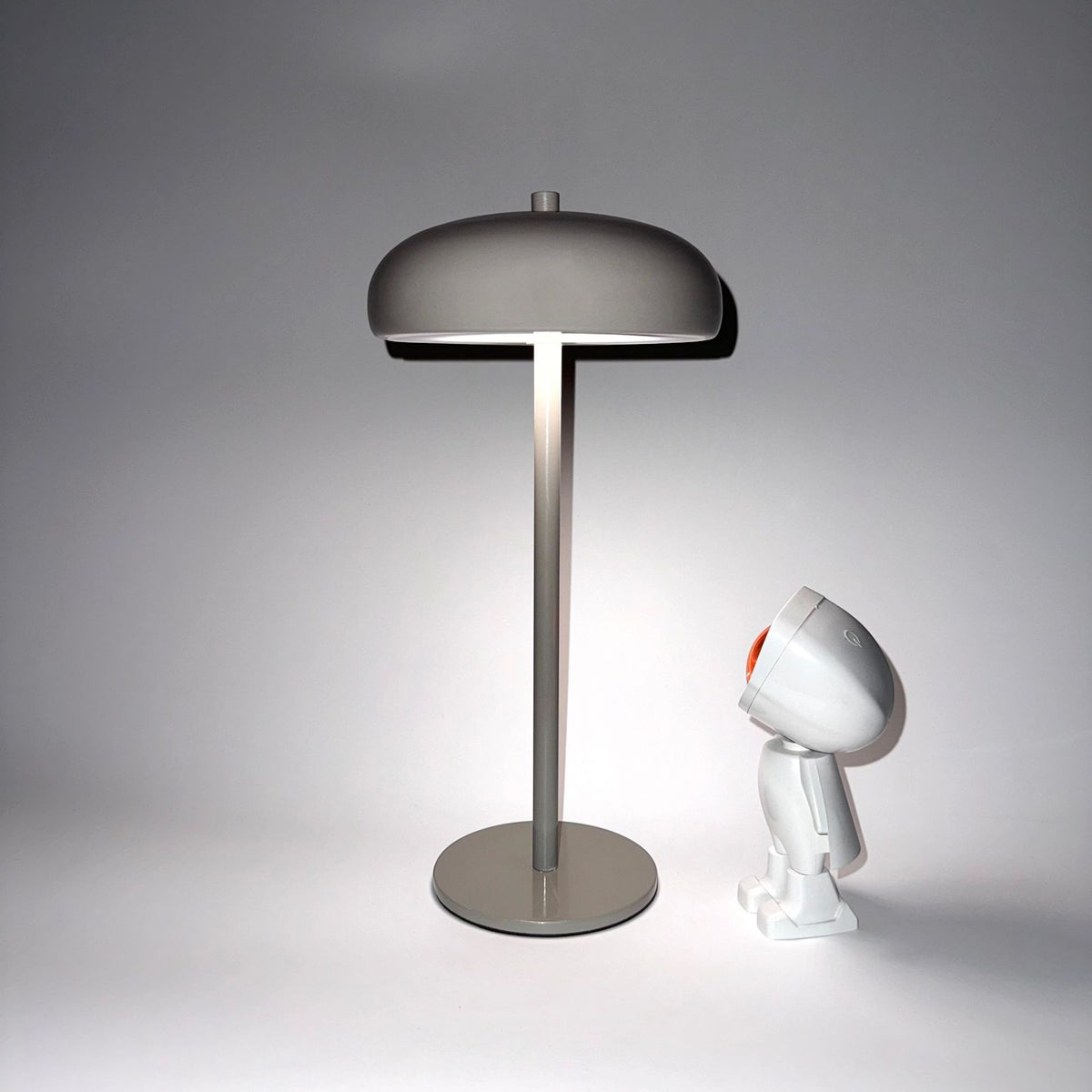 Lampe champignon minimaliste Lumeoo rechargeable gris taupe au design moderne sur fond blanc