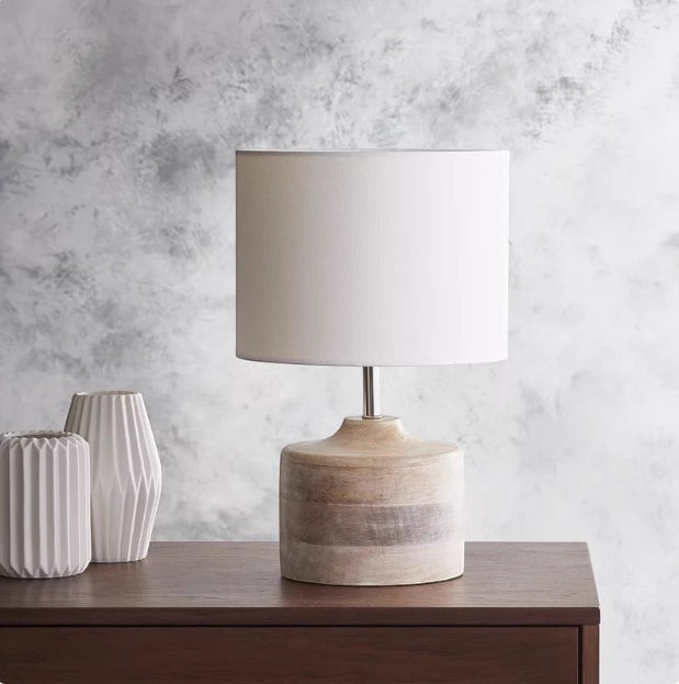 Lampe de chevet Lumeoo avec base en bois naturel et abat-jour cylindrique blanc sur une commode en bois