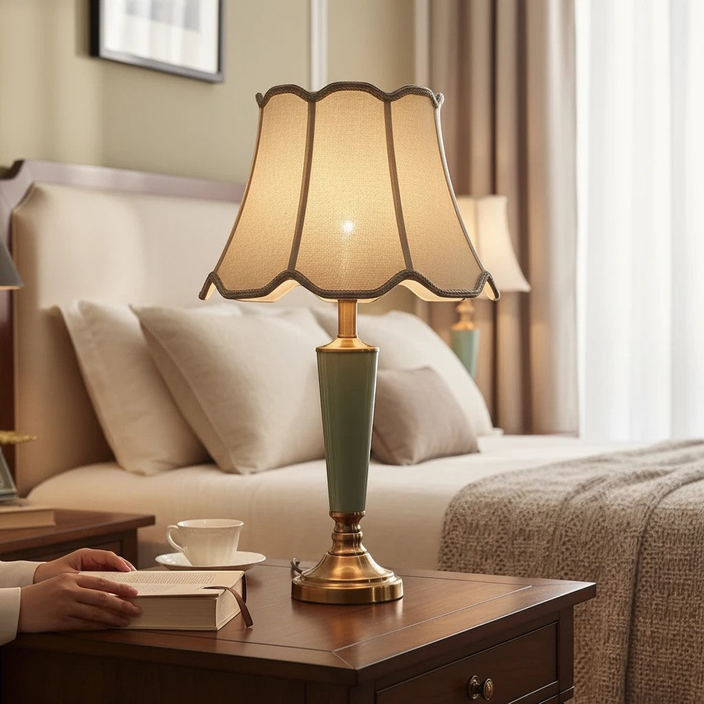 Lampe de chevet Lumeoo en céramique vert sauge avec abat-jour festonné beige sur une table de nuit en bois