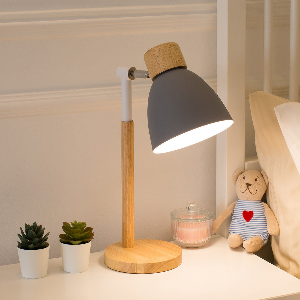 Lampe de chevet Lumeoo grise et bois au design scandinave sur une table de nuit avec un petit ours en peluche