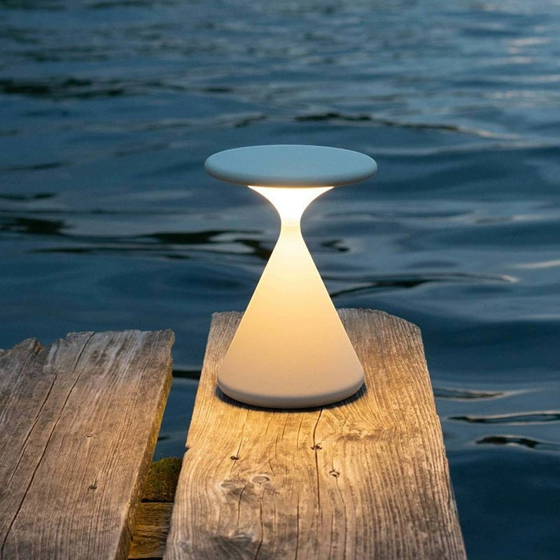 Lampe de chevet minimaliste Lumeoo PASTILUX couleur pastel diffusant une lumière douce sur un ponton en bois