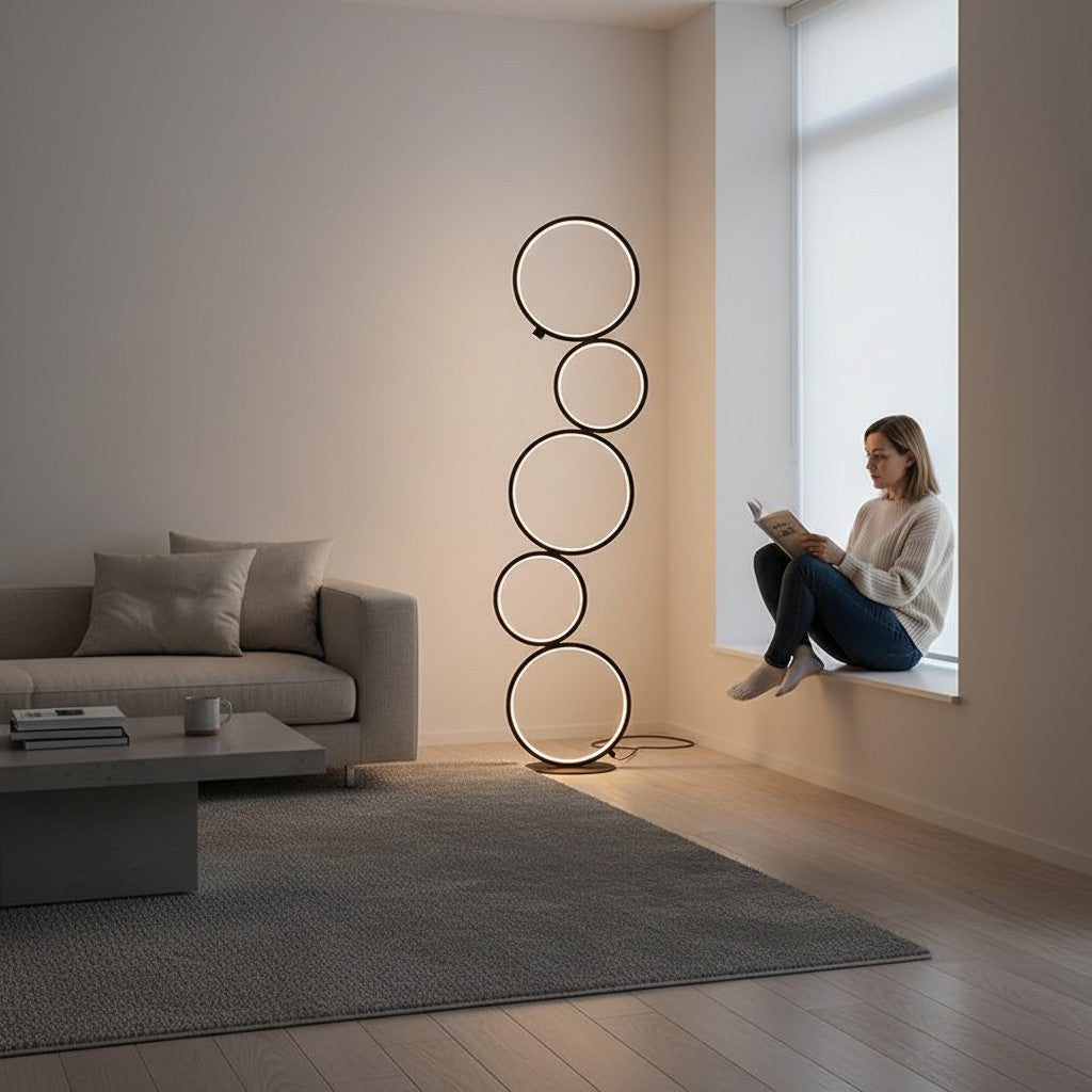 Lampe Lumeoo design moderne avec anneaux lumineux circulaires noirs dans un salon minimaliste avec une femme lisant
