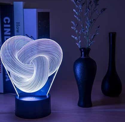 Lampe LED 3D Lumeoo en acrylique torsadé avec éclairage tactile coloré, posée sur une table de chevet moderne.