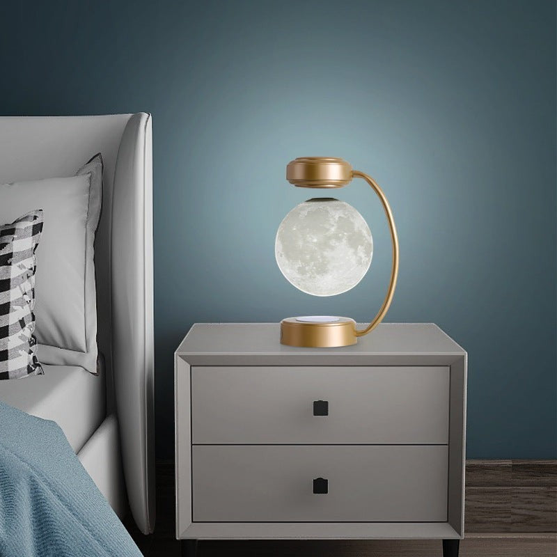 Lampe lune Lumeoo en lévitation magnétique avec base dorée, posée sur une table de chevet pour une ambiance moderne.