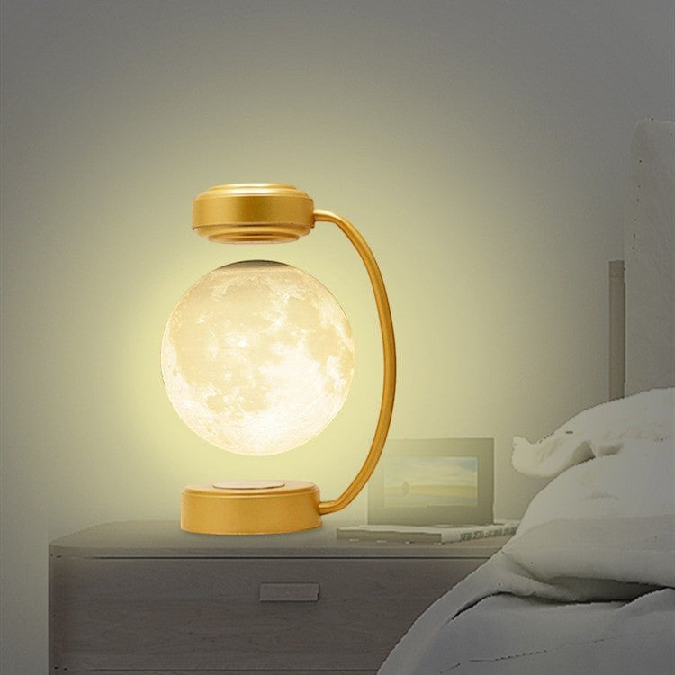 Lampe lune Lumeoo en lévitation magnétique avec support doré, diffusant une lumière LED chaude sur une table de nuit.