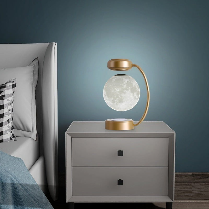 Lampe lune Lumeoo en lévitation magnétique avec support doré sur une table de chevet moderne