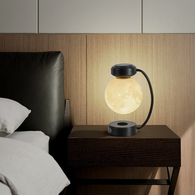 Lampe lune Lumeoo en lévitation magnétique avec support noir moderne diffusant une lumière LED chaude sur une table