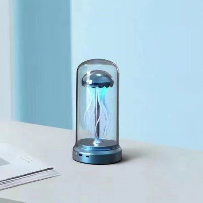 Lampe d'ambiance méduse Lumeoo avec dôme en verre et éclairage LED bleu apaisant sur un bureau