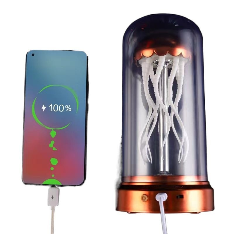 Lampe d'ambiance méduse Lumeoo avec dôme transparent, tentacules blanches et base cuivrée, en cours de charge par USB