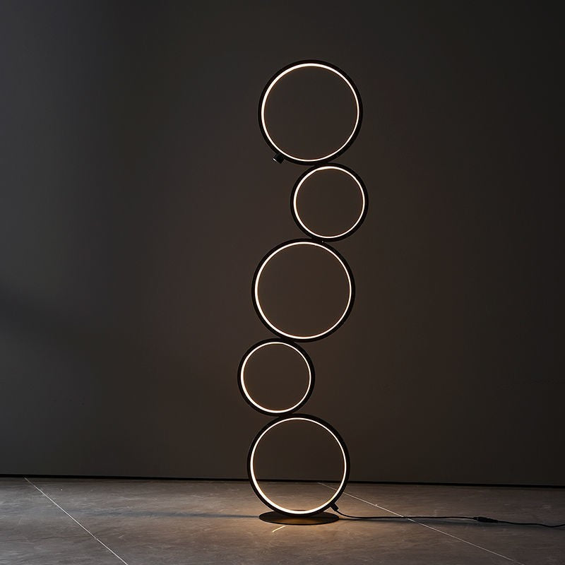Lampe sur pied Lumeoo au design minimaliste composée de cinq anneaux lumineux noirs empilés pour une ambiance moderne