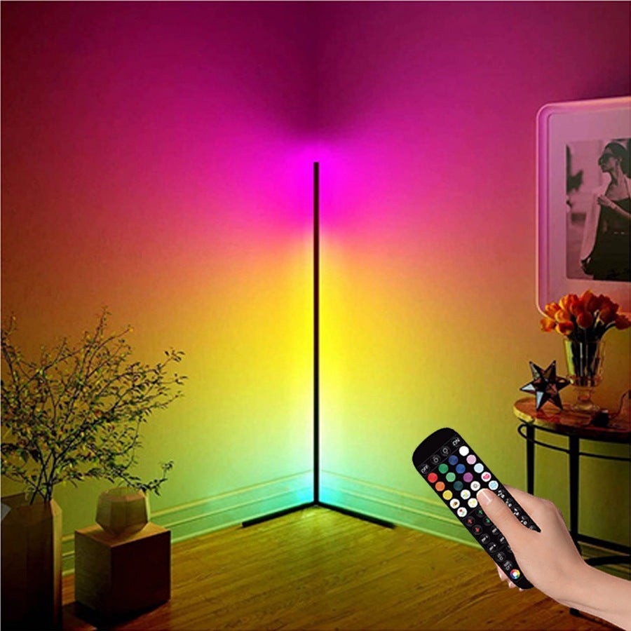 Lampe sur pied Lumeoo RGB connectée dans un angle de salon diffusant une lumière colorée avec télécommande