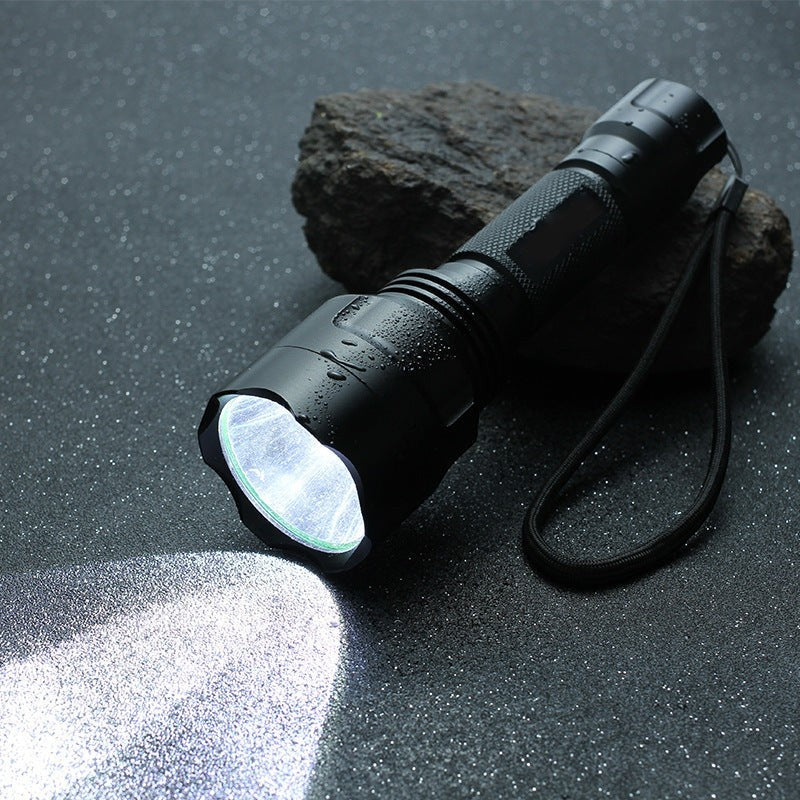 Lampe de poche LED Lumeoo BEAMOX en aluminium noir, rechargeable, puissante, éclairant une surface sombre.