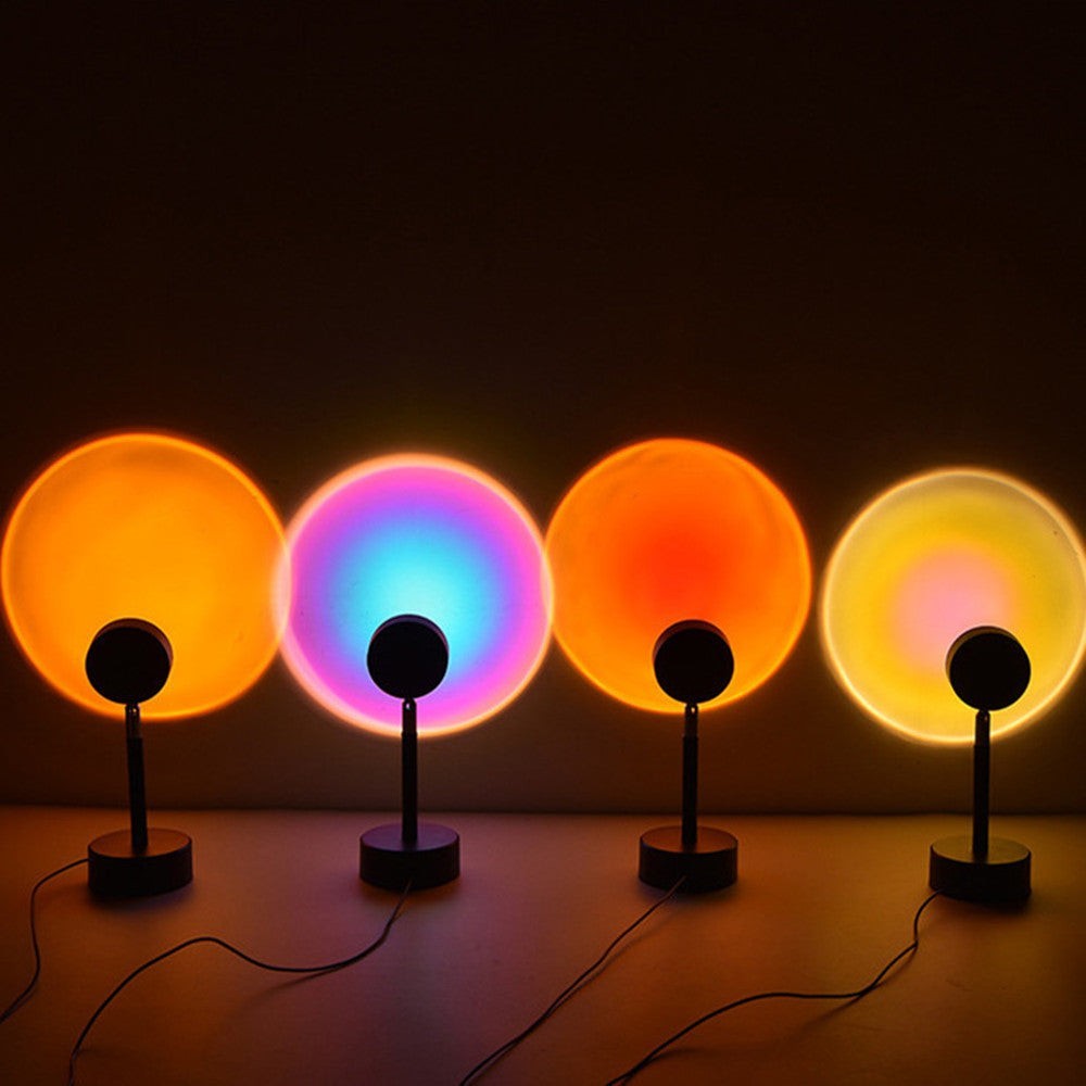Quatre lampes projecteur Lumeoo diffusant des halos lumineux colorés rappelant le coucher de soleil sur un mur sombre