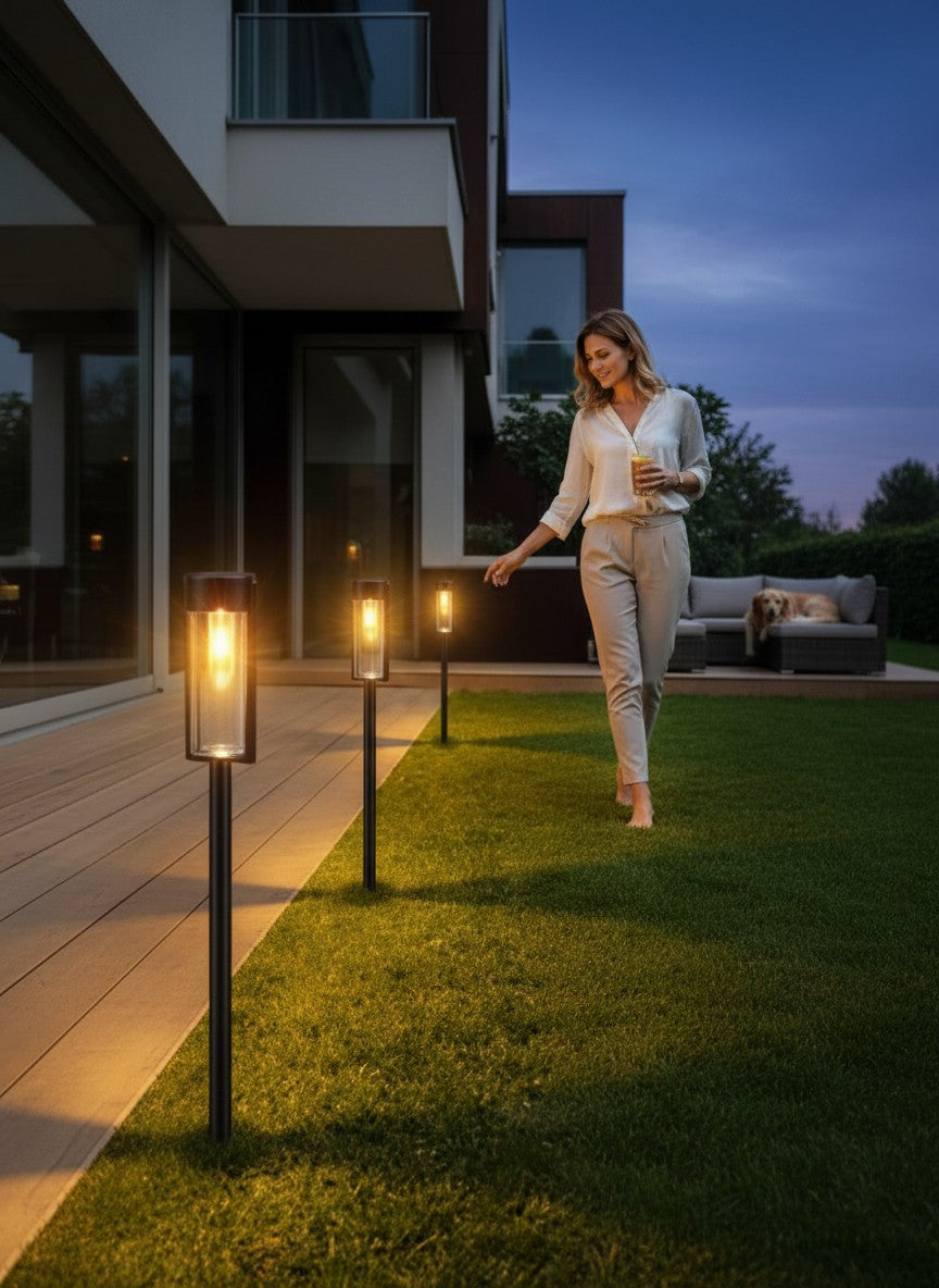 Lumeoo lampe solaire extérieur à filament tungstène sur piquet illuminant une terrasse avec une femme en arrière-plan