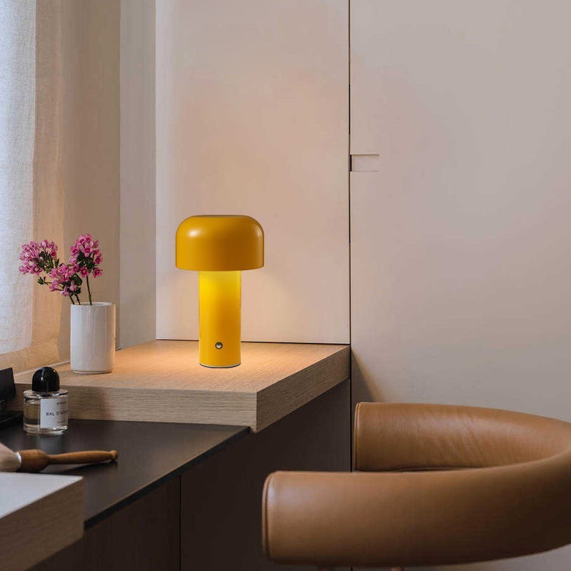 Lampe de table champignon Lumeoo jaune tactile au design moderne posée sur un bureau en bois dans un intérieur épuré