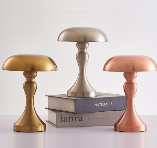 Trois lampes de table champignon Lumeoo en métal doré, argenté et cuivré posées sur des livres pour une ambiance chic