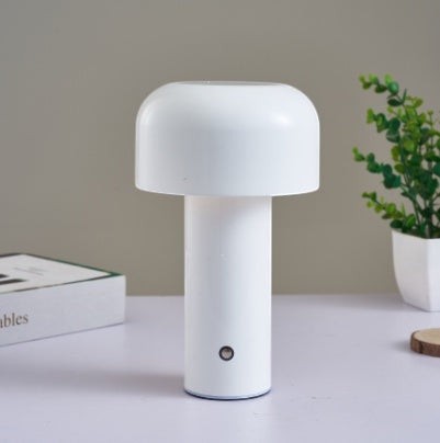 Lampe de table champignon Lumeoo blanche tactile au design minimaliste posée sur un bureau avec une plante