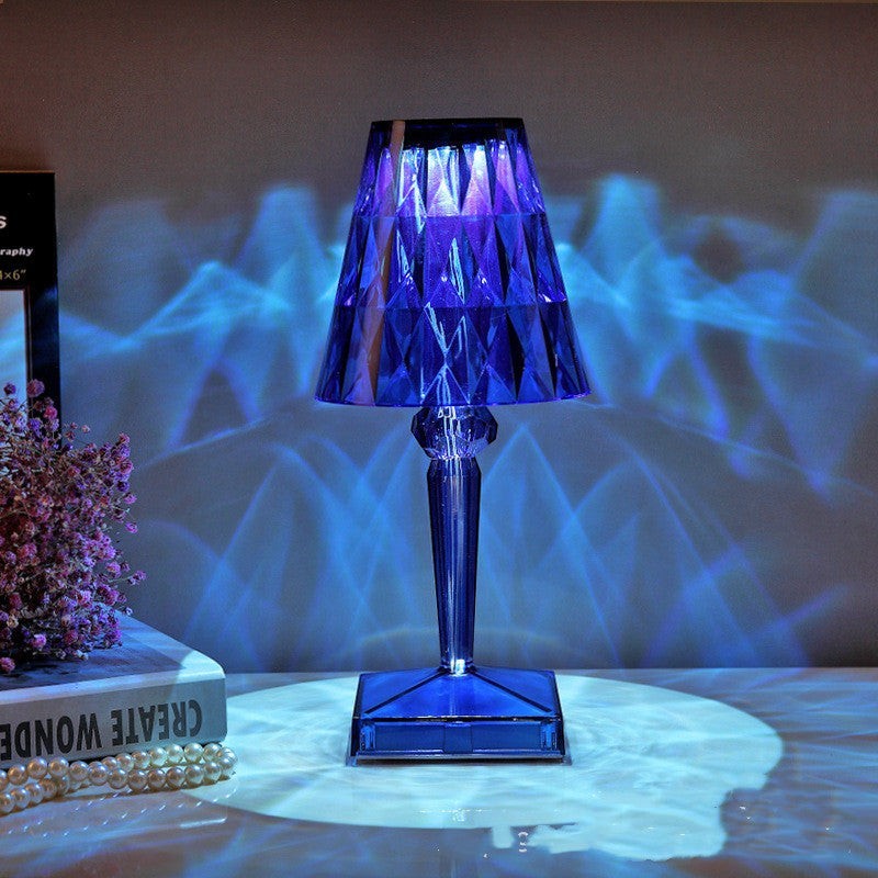 Lampe de table Lumeoo CRYSTIX en cristal bleu rechargeable diffusant des reflets lumineux décoratifs sur un mur