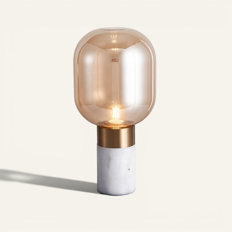 Lampe de table design Lumeoo avec globe en verre ambré, base en marbre blanc et détails dorés, style contemporain.