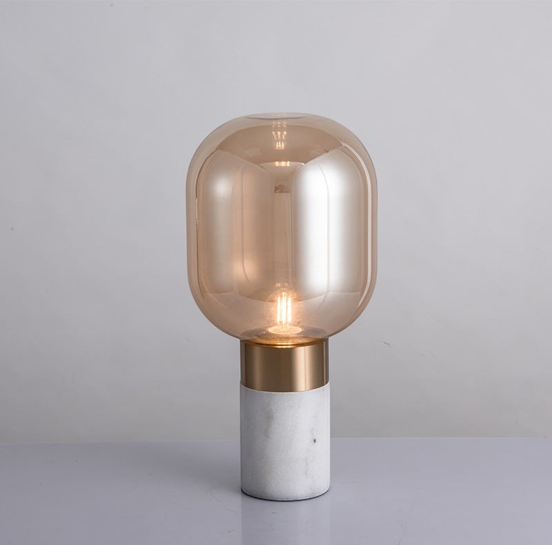 Lampe de table design Lumeoo avec globe en verre ambré, base en marbre blanc et détails en métal doré