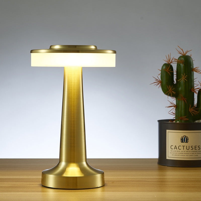 Lampe de table sans fil Lumeoo KARONO en métal doré avec diffuseur lumineux circulaire sur une table en bois