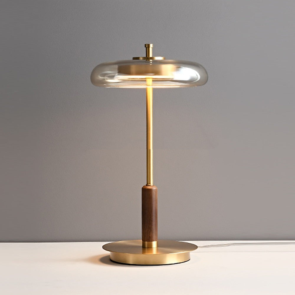 Lampe de table Lumeoo design en laiton doré et bois avec un abat-jour en verre transparent pour une lumière douce
