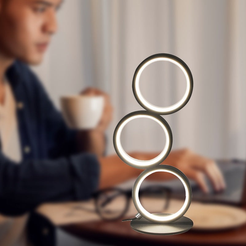 Lampe de table LED tactile Lumeoo avec trois anneaux lumineux sur un bureau, créant une ambiance chaleureuse.