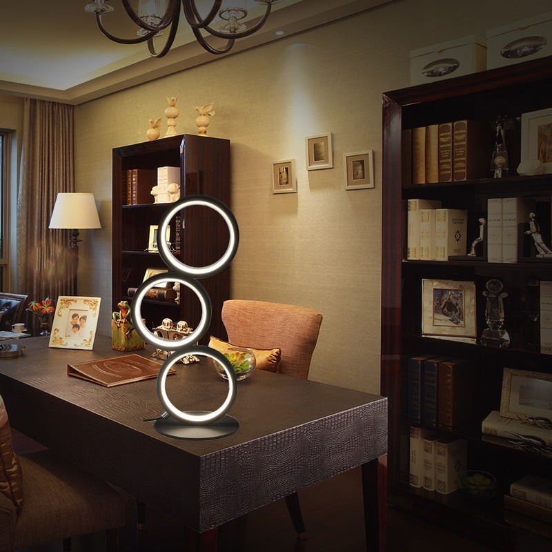 Lampe de table LED tactile Lumeoo avec trois anneaux lumineux circulaires sur un bureau dans un salon élégant