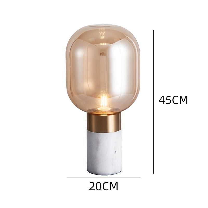 Lampe de table design Lumeoo avec globe en verre ambré, base en marbre blanc et détails dorés, style contemporain.