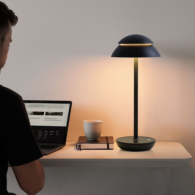 Lampe de table Lumeoo SKANDOR noire au design nordique minimaliste, sans fil et rechargeable sur un bureau moderne.