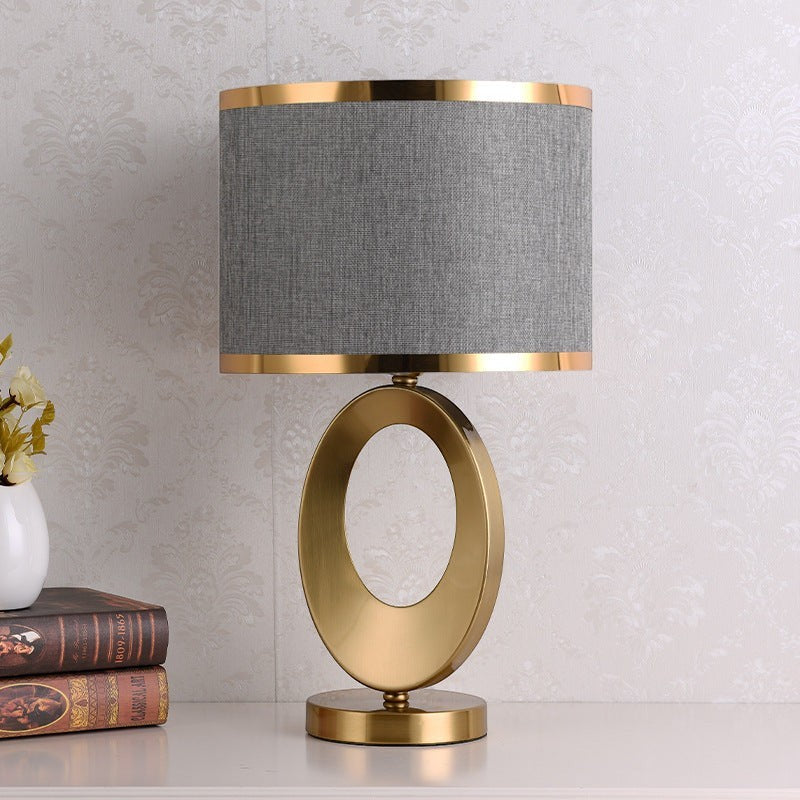 Lampe de table Lumeoo ORBILUX avec pied ovale en métal doré et abat-jour cylindrique en tissu gris pour salon