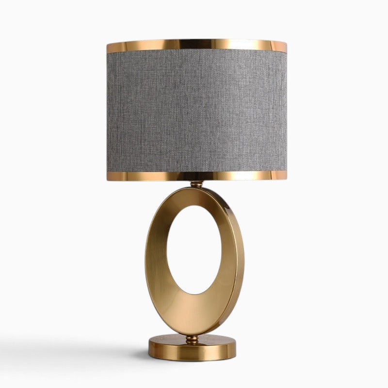 Lampe de table Lumeoo ORBILUX avec pied ovale en métal doré et abat-jour cylindrique en tissu gris pour salon