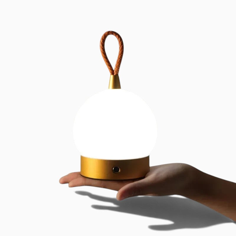 Lumeoo lampe de table rechargeable style camping avec globe lumineux blanc et poignée en cuir tenue dans la main