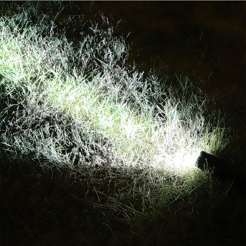 Faisceau lumineux puissant de la lampe torche tactique Lumeoo éclairant l'herbe dans l'obscurité nocturne