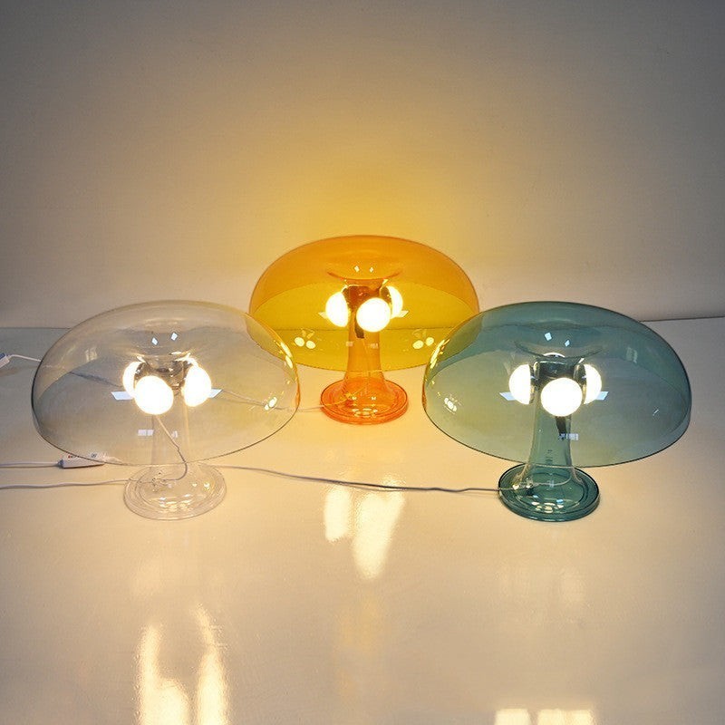Trois lampes champignon Lumeoo en verre transparent, orange et bleu diffusant une lumière douce et chaleureuse.